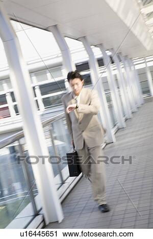 Businessman looking at wristwatch, blurred motion View Large Photo Image Stock Image - Businessman looking at wristwatch, blurred motion. Fotosearch