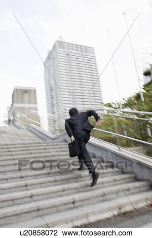 Stock Image - Businessman running up steps. Fotosearch