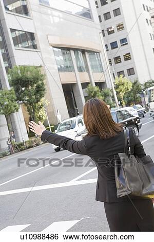 Stock Photograph - Businesswoman hailing taxi. Fotosearch