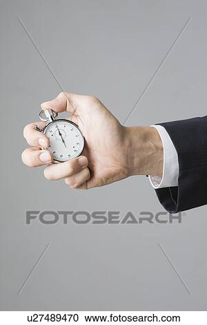 Stock Image - Hand of businessman holding stopwatch. Fotosearch