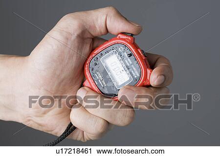 Stock Image - Hand of man holding stopwatch. Fotosearch