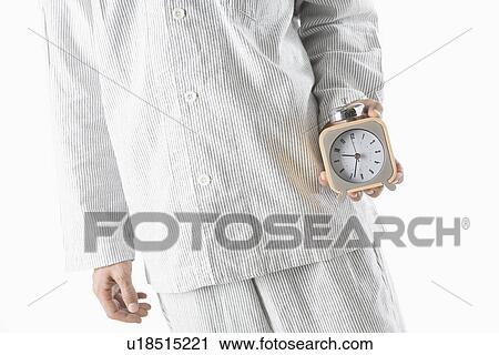 Stock Image - Man holding alarm clock. Fotosearch