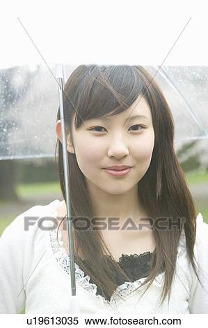 Portrait of a woman holding an umbrella, smiling and looking at camera, front view, Japan View Large Photo Image Stock Photography - Portrait of a woman holding an umbrella, smiling and looking at camera, front view, Japan. Fotosearch