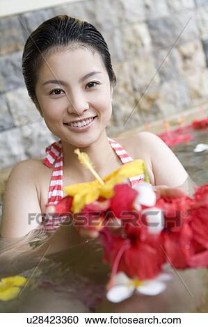 Stock Image - Young woman holding out flowers, Saipan. Fotosearch
