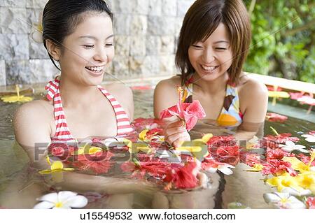 Stock Image - Young women in a bath full of flowers, Saipan. Fotosearch