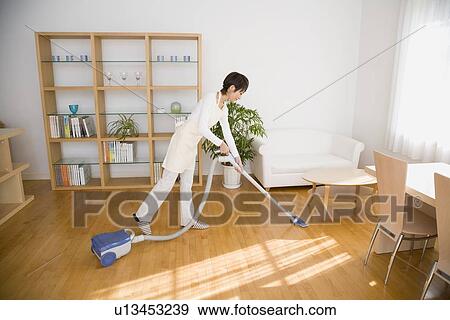 Housewife vacuuming room View Large Photo Image Stock Photo - Housewife vacuuming room. Fotosearch