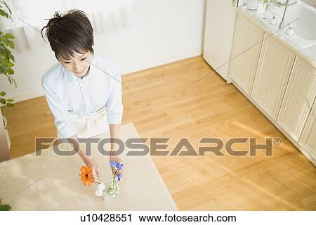 Stock Image - Young woman arranging flower. Fotosearch