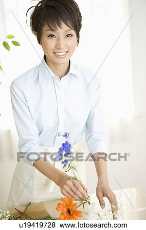 Stock Photo - Young woman arranging flower. Fotosearch