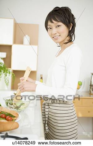 Young woman cooking in kitchen View Large Photo Image Stock Photo - Young woman cooking in kitchen. Fotosearch