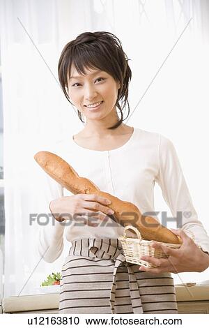 Stock Image - Young woman holding baguette. Fotosearch