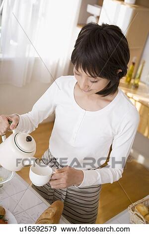Young woman pouring coffee View Large Photo Image Stock Photo - Young woman pouring coffee. Fotosearch