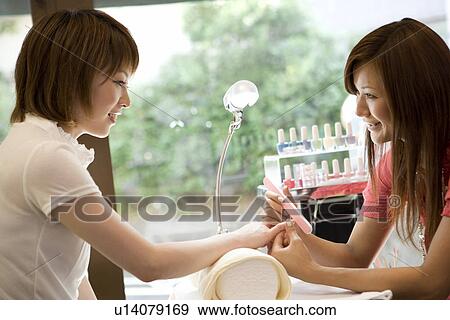 Stock Photo - Beautician filing nails. Fotosearch