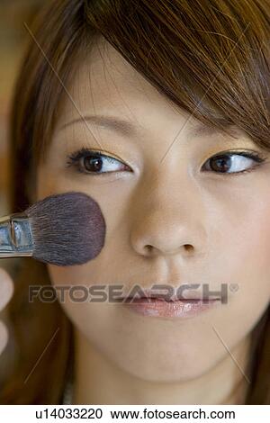 Stock Image - Young woman applying make up. Fotosearch