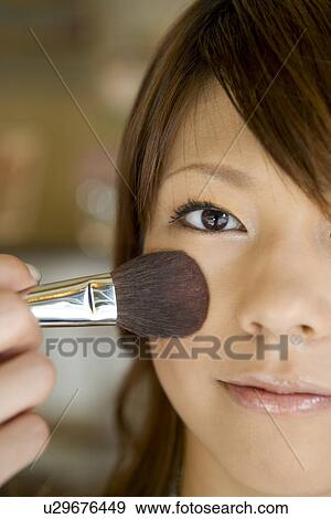 Stock Photo - Young woman applying make up. Fotosearch