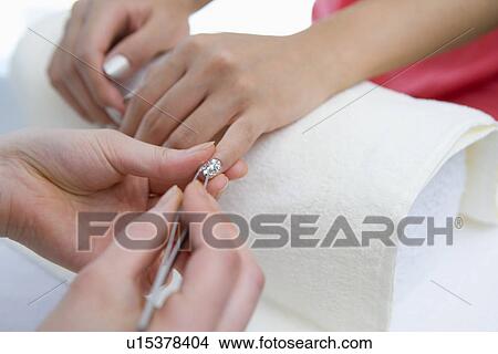 Picture - Young woman applying manicure at nail salon. Fotosearch