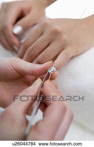 Picture - Young woman applying manicure at nail salon. Fotosearch