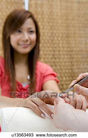 Young woman applying manicure at nail salon View Large Photo Image Stock Image - Young woman applying manicure at nail salon. Fotosearch