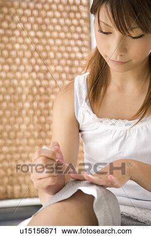 Stock Image - Young woman applying manicure. Fotosearch
