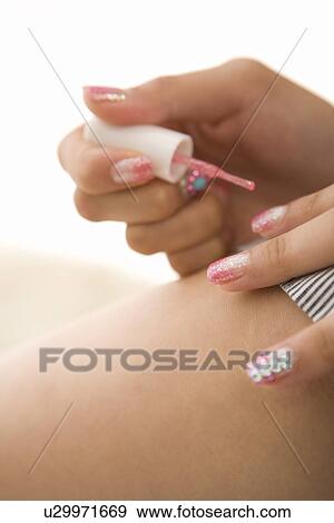 Stock Photo - Young woman applying manicure. Fotosearch