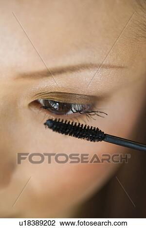Stock Image - Young woman applying mascara. Fotosearch