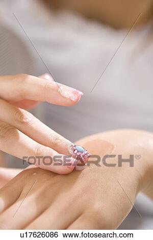 Stock Photograph - Young woman applying moisturizer. Fotosearch