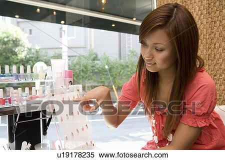 Stock Photography - Young woman choosing artificial nails. Fotosearch