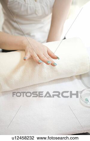 Stock Image - Young woman looking at manicure. Fotosearch