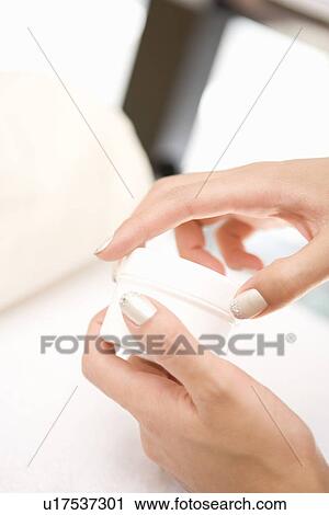 Stock Image - Young woman opening moisturizer. Fotosearch