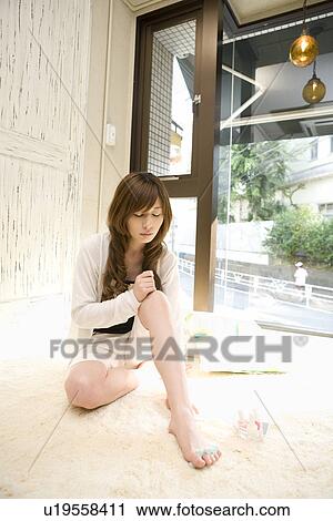 Stock Image - Young woman painting toe nails. Fotosearch