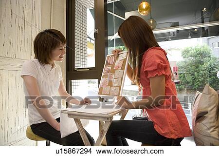 Picture - Young woman talking with beautician at nail salon. Fotosearch
