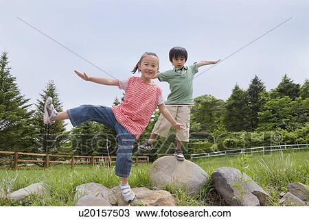 Stock Image - Boy and girl balancing on rocks. Fotosearch