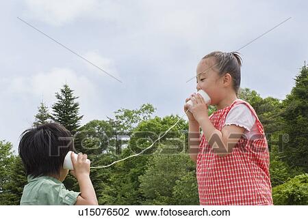 Stock Image - Boy and girl talking with string telephone. Fotosearch