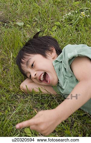 Boy lying on grass field View Large Photo Image Picture - Boy lying on grass field. Fotosearch