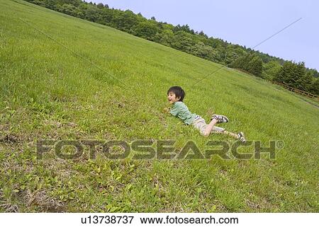 Boy lying on grass field View Large Photo Image Stock Photo - Boy lying on grass field. Fotosearch