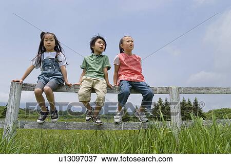 Stock Photo - Children sitting on fence. Fotosearch