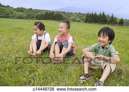 Children sitting on grass field View Large Photo Image Stock Photo - Children sitting on grass field. Fotosearch