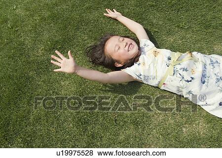 Girl lying on grass View Large Photo Image Stock Photo - Girl lying on grass. Fotosearch