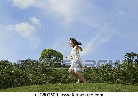 Stock Image - Girl running on grass field. Fotosearch