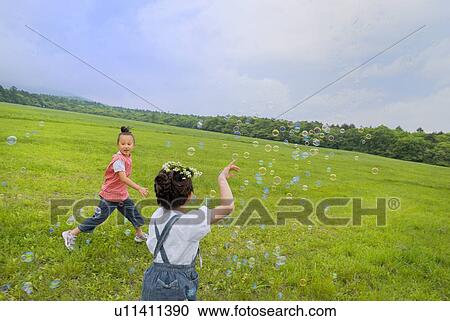 Stock Image - Girls playing with bubble. Fotosearch