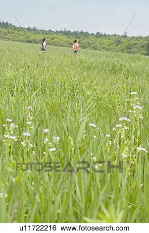 Stock Photograph - Girls running on grass field. Fotosearch