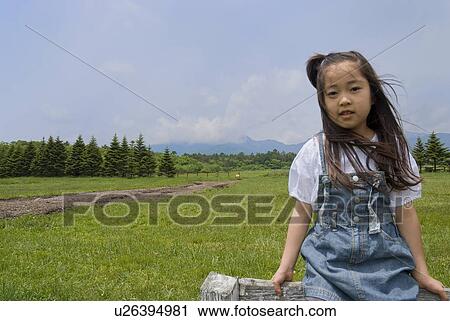 Stock Image - Portrait of a girl sitting on fence. Fotosearch