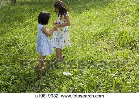 Two girls playing on grass field View Large Photo Image Stock Image - Two girls playing on grass field. Fotosearch