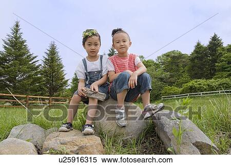 Stock Photography - Two girls sitting on rock. Fotosearch
