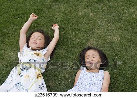 Stock Photo - Two girls sleeping on grass. Fotosearch