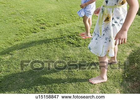 Two girls standing on grass field View Large Photo Image Stock Photo - Two girls standing on grass field. Fotosearch