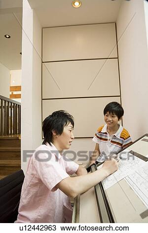 Stock Image - Boy looking at father drawing. Fotosearch