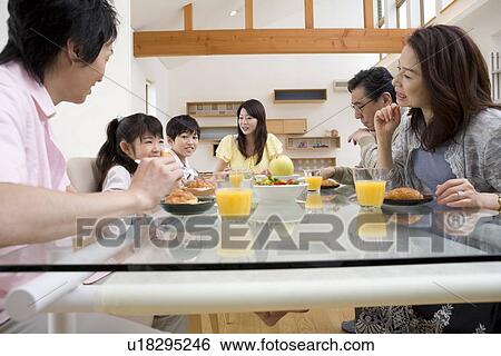 Family sitting at dining table View Large Photo Image Stock Photograph - Family sitting at dining table. Fotosearch