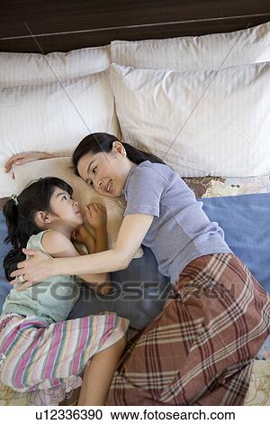 Stock Image - Grandmother and granddaughter sleeping on bed. Fotosearch