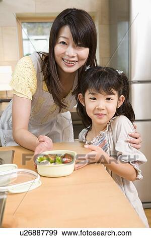 Stock Photo - Mother and daughter showing lunchbox. Fotosearch