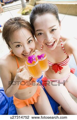 Two young women in bikini drinking juice View Large Photo Image Stock Image - Two young women in bikini drinking juice. Fotosearch